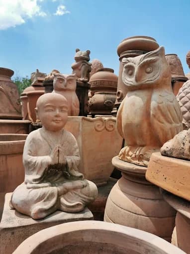 Sculture artigianali in terracotta nello showroom Faraone Vasi a Napoli: monaco e gufi decorativi